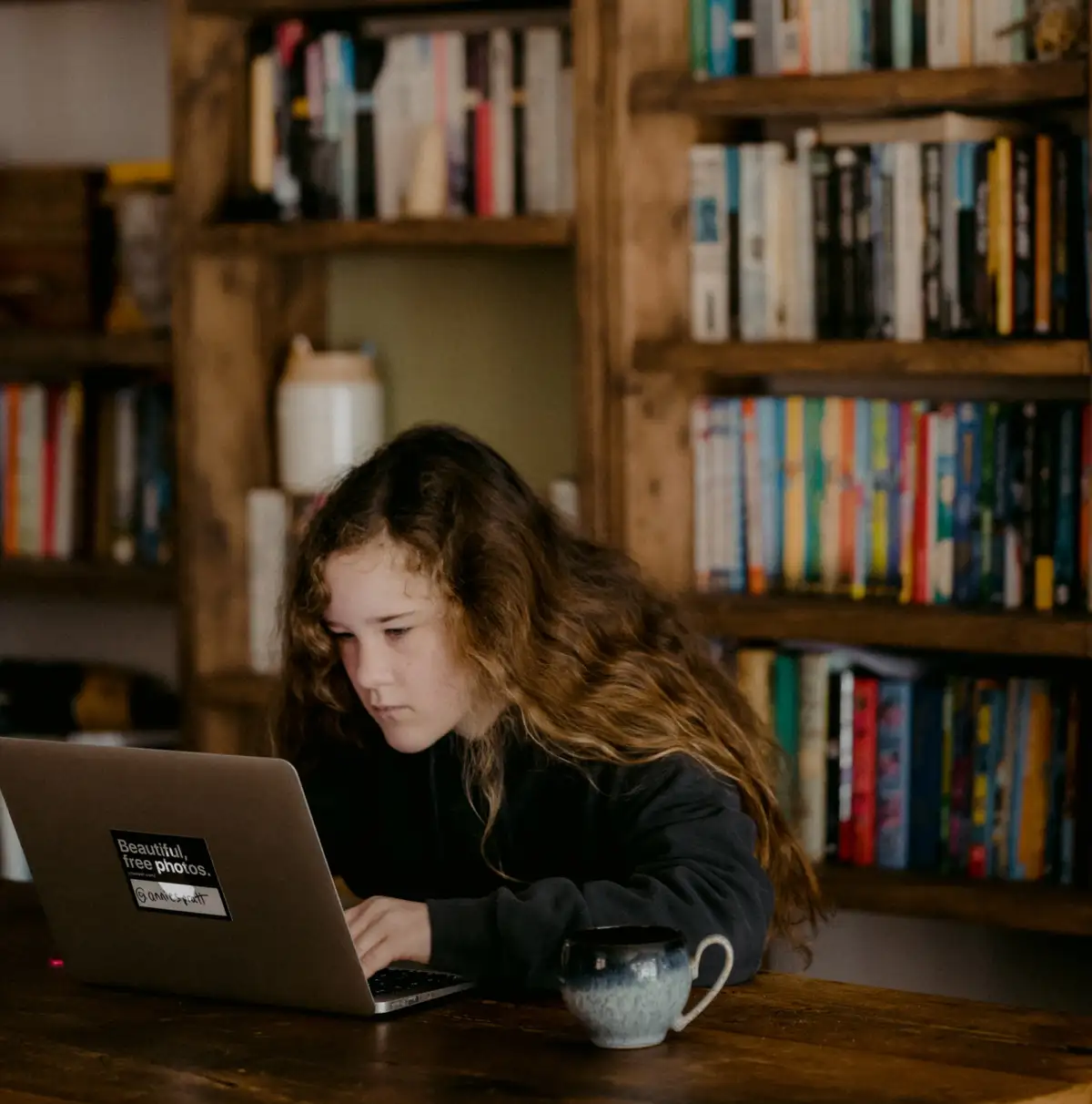 A young girl working on laptop at a book cafe